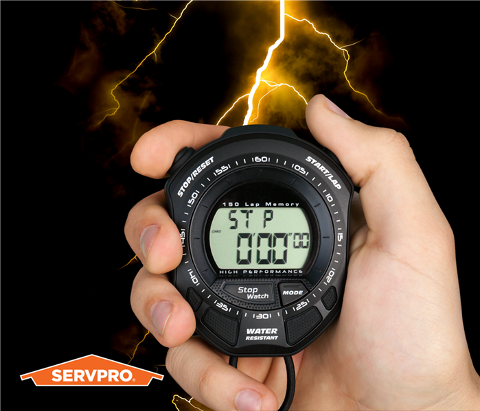 stop watch in a hand in front of a lightning sky background, SERVPRO logo in the corner