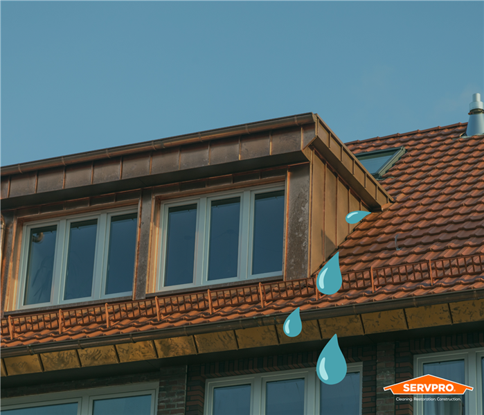 roof leak caused by water damage in arlington texas, servpro logo, red tile roof on house with water dripping